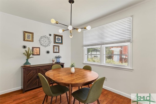 dining space featuring crown molding, baseboards, a chandelier, and wood finished floors