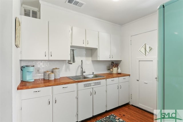 kitchen with visible vents, wood finished floors, crown molding, white cabinetry, and a sink