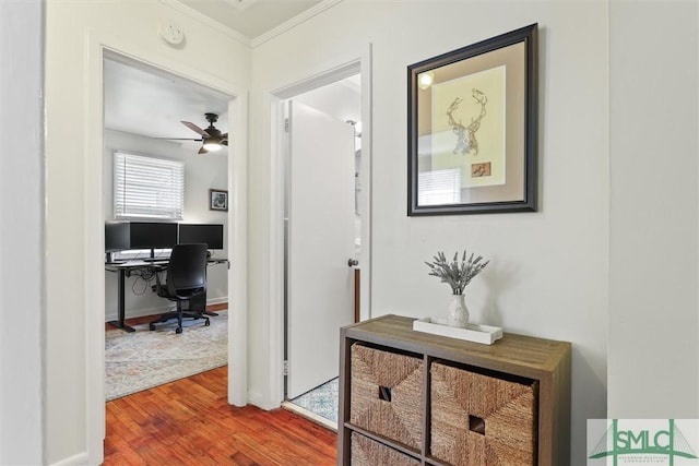 corridor with crown molding, baseboards, and wood finished floors