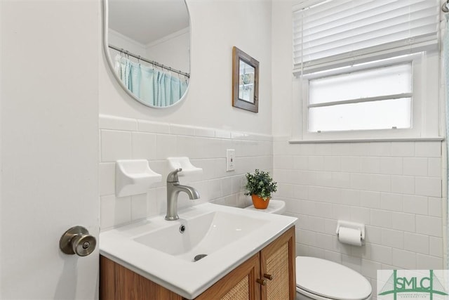 bathroom featuring tile walls, a wainscoted wall, vanity, and toilet