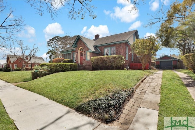 bungalow featuring driveway, brick siding, a chimney, an outdoor structure, and a front yard