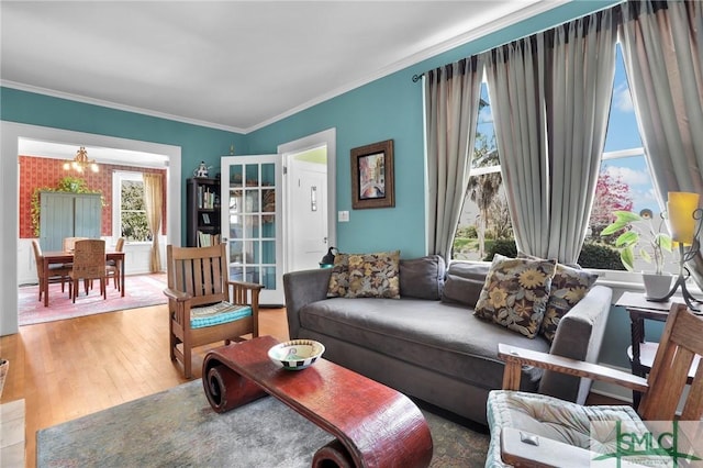 living room with a chandelier, ornamental molding, and wood finished floors