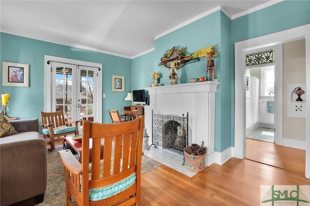 living area with a healthy amount of sunlight, light wood-style floors, ornamental molding, and french doors