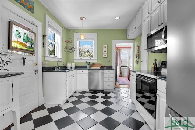 kitchen featuring dark floors, a sink, white cabinetry, appliances with stainless steel finishes, and dark countertops