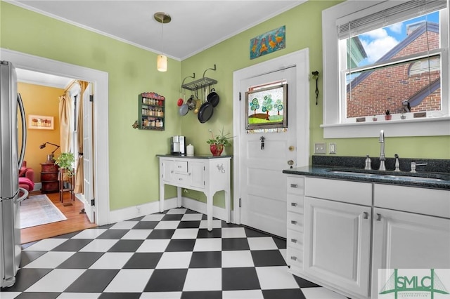 interior space with crown molding, dark floors, freestanding refrigerator, and a sink