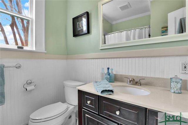 full bathroom with toilet, visible vents, vanity, ornamental molding, and wainscoting