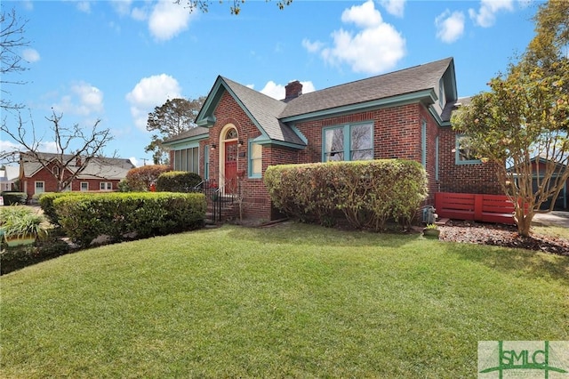 view of front of home with a front yard, brick siding, and a chimney