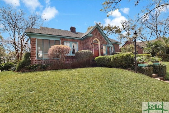 view of front of property with brick siding, a front lawn, and a chimney