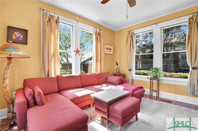 living area featuring a ceiling fan, baseboards, visible vents, and wood finished floors