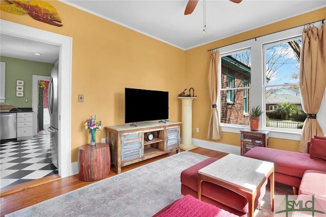 living room with ornamental molding, wood finished floors, a ceiling fan, and baseboards