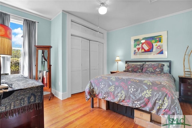 bedroom with baseboards, a closet, wood finished floors, and crown molding