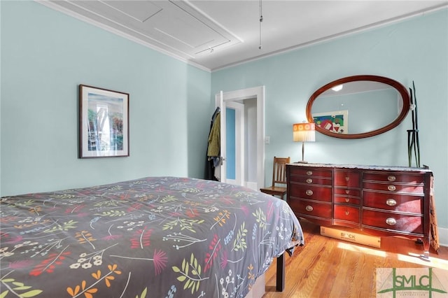 bedroom featuring ornamental molding and wood finished floors