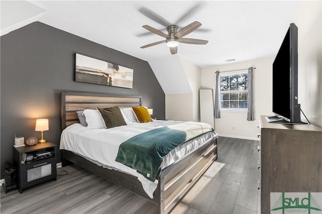 bedroom featuring visible vents, lofted ceiling, baseboards, and wood finished floors