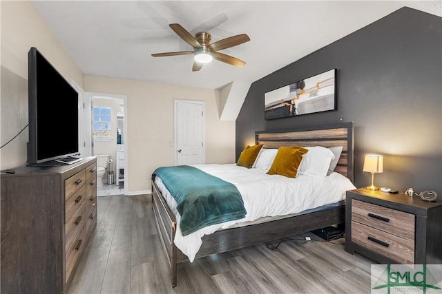 bedroom with ceiling fan, wood finished floors, baseboards, and connected bathroom