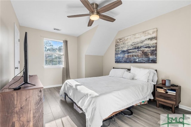 bedroom with wood finished floors, visible vents, baseboards, ceiling fan, and vaulted ceiling