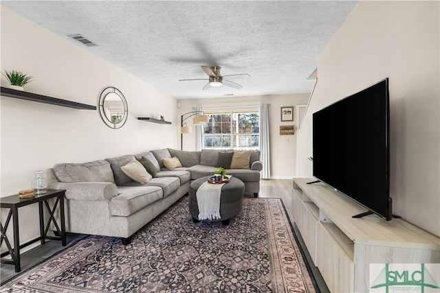 living area with visible vents, a textured ceiling, wood finished floors, and a ceiling fan