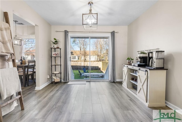 entryway featuring an inviting chandelier, plenty of natural light, wood finished floors, and baseboards