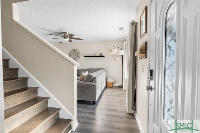 entryway featuring stairway, ceiling fan, visible vents, and wood finished floors