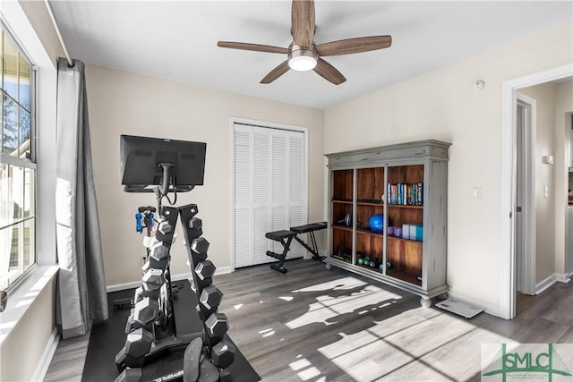 exercise area with baseboards, wood finished floors, and a ceiling fan