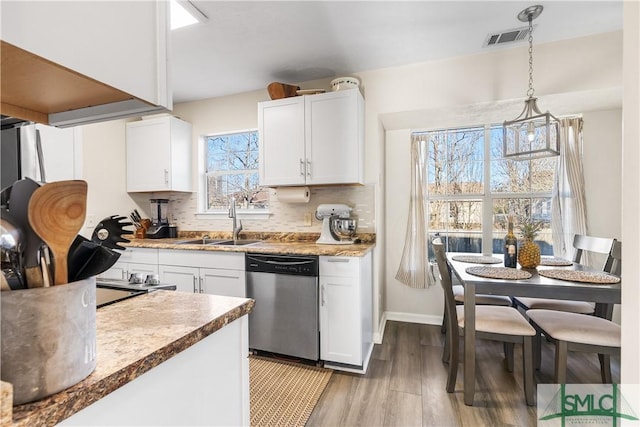 kitchen with visible vents, a sink, tasteful backsplash, stainless steel dishwasher, and white cabinets