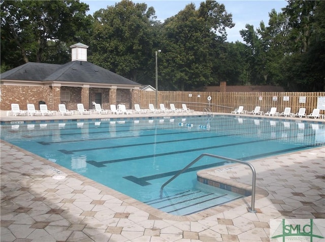 community pool with a patio area and fence