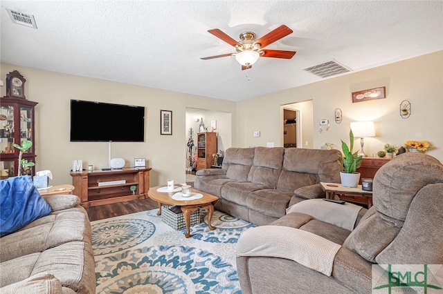 living area with a ceiling fan, visible vents, a textured ceiling, and wood finished floors