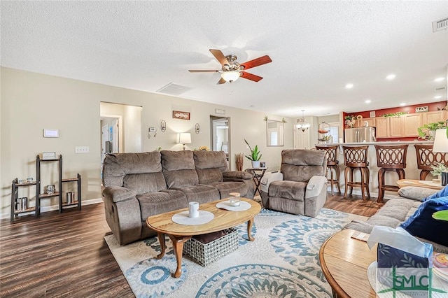 living area with a textured ceiling, wood finished floors, visible vents, and a ceiling fan