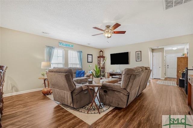 living area with a textured ceiling, wood finished floors, and visible vents