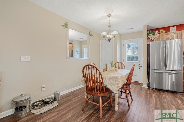 dining space with a notable chandelier, dark wood-style flooring, a textured ceiling, and baseboards