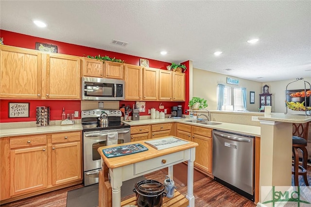 kitchen with visible vents, a peninsula, stainless steel appliances, light countertops, and a sink