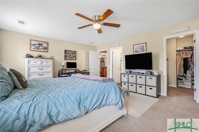 bedroom featuring a textured ceiling, ceiling fan, visible vents, a spacious closet, and carpet