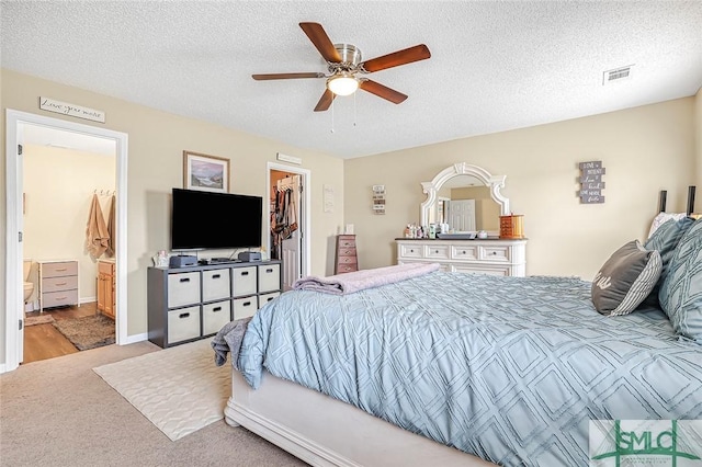 carpeted bedroom with a closet, visible vents, a spacious closet, and a textured ceiling