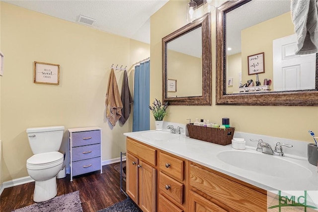 bathroom featuring toilet, visible vents, a sink, and wood finished floors