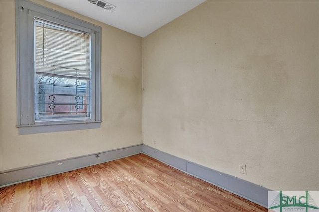 empty room with light wood-style flooring, visible vents, and baseboards