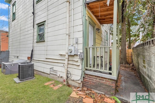 view of side of property with fence, a lawn, and central air condition unit