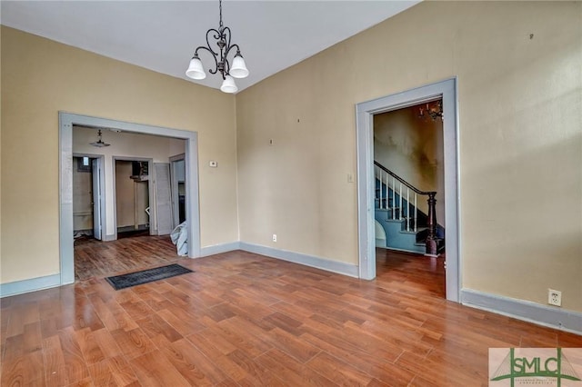 unfurnished dining area with a chandelier, light wood finished floors, stairway, and baseboards