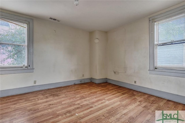 empty room featuring light wood finished floors, visible vents, and baseboards