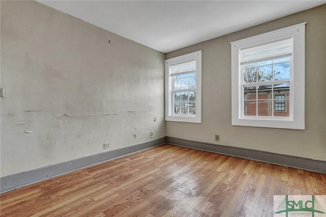 spare room with baseboards and wood finished floors