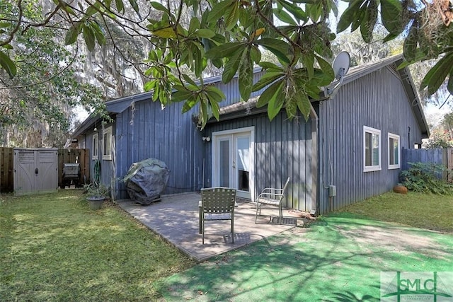 back of house featuring an outbuilding, a yard, a patio, a storage shed, and fence