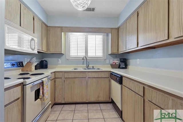 kitchen featuring light tile patterned flooring, white appliances, a sink, visible vents, and light countertops