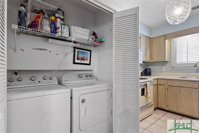 laundry room featuring a sink, laundry area, light tile patterned flooring, and washing machine and clothes dryer