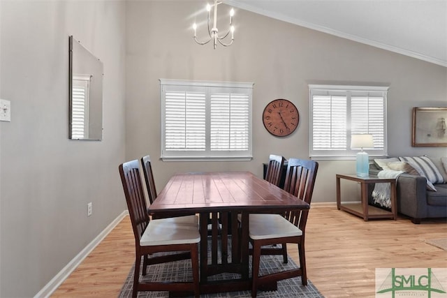 dining room with plenty of natural light, light wood-style flooring, vaulted ceiling, and a notable chandelier