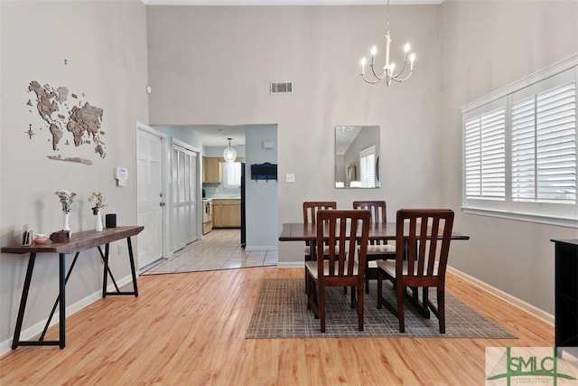 dining space featuring baseboards, a chandelier, visible vents, and light wood-style floors