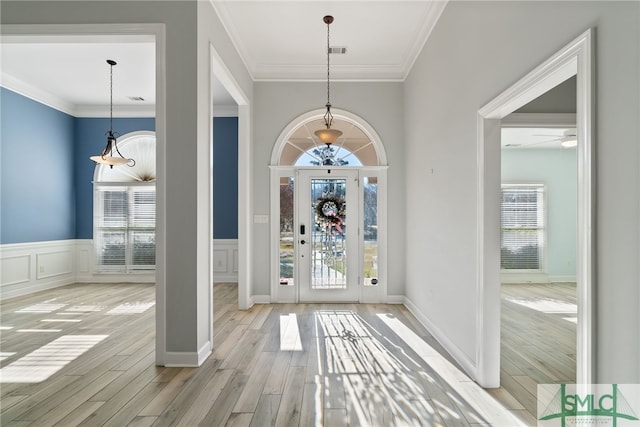 entrance foyer featuring a healthy amount of sunlight, crown molding, and wood finished floors