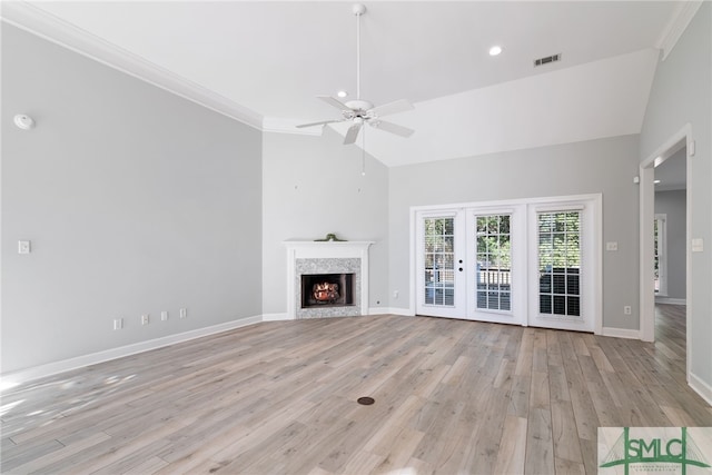 unfurnished living room featuring visible vents, baseboards, light wood-style flooring, a lit fireplace, and french doors