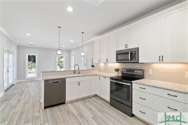 kitchen featuring a peninsula, a sink, appliances with stainless steel finishes, backsplash, and crown molding