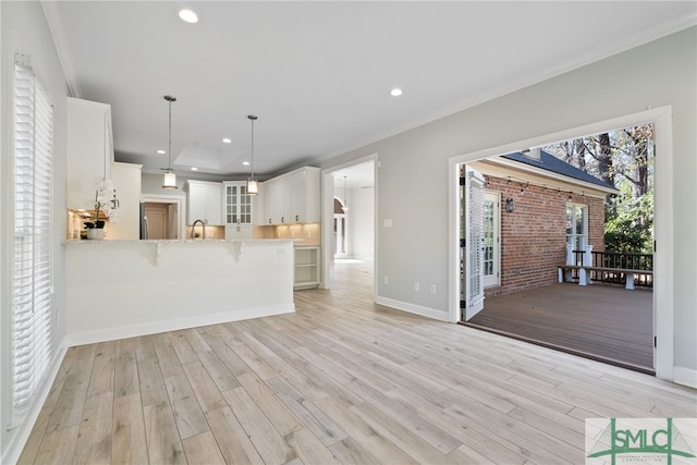 interior space with light wood-style floors, a breakfast bar area, glass insert cabinets, and crown molding