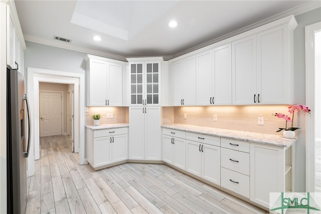 kitchen with visible vents, white cabinets, stainless steel fridge, and backsplash