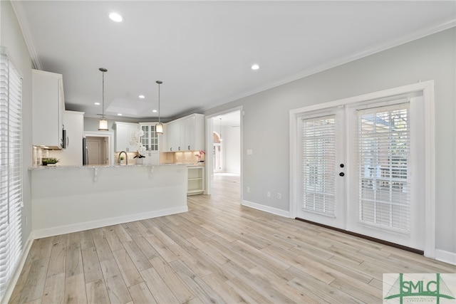 kitchen featuring a peninsula, a kitchen breakfast bar, french doors, light wood-type flooring, and crown molding