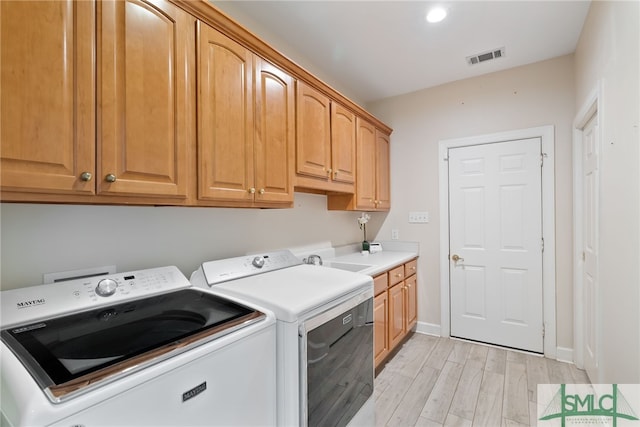 laundry area with washing machine and dryer, light wood-style flooring, visible vents, baseboards, and cabinet space